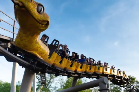 Un train de montagnes russes en forme de serpent jaune emmène des passagers joyeux dans le ciel bleu. Une idée pour que faire ce dimanche dans le 43 ?