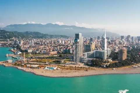 Widok na nowoczesne budynki Batumi i turkusowe morze. W tle góry, idealny batumi klimat do wypoczynku.