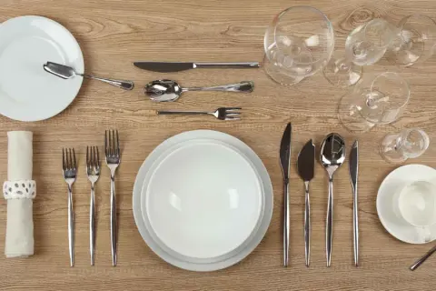 Une **fourchette sur la table** est prête pour le dîner, aux côtés d'assiettes, de verres et d'autres couverts.