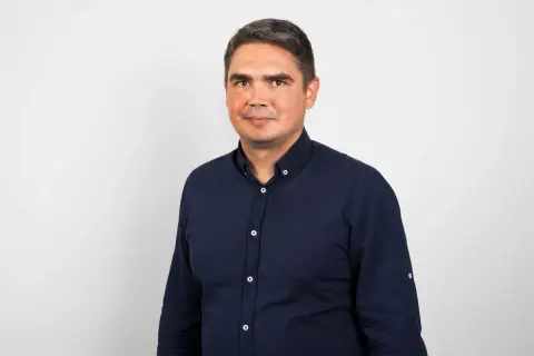 Portret mężczyzny w granatowej koszuli na jasnym tle.