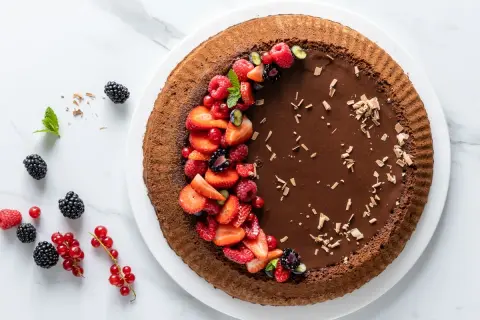 Torta Lindt al cioccolato fondente, decorata con fragole, lamponi, ribes e mirtilli. Un capolavoro goloso.