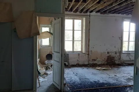 Intérieur délabré d'une maison abandonnée dans les Ardennes, avec un papier peint déchiré, un plafond effondré et une vieille cuvette de toilette. Urbex Ardennes.