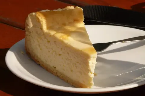 Pyszny sernik z 2 kg sera z wiaderka na talerzu, gotowy do zjedzenia. Idealny na deser.