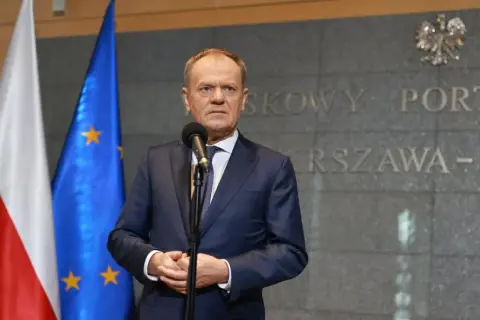 Premier Tusk, stojąc przed flagami Polski i UE, przemawia na tle napisu "Warszawa-Okęcie". Kto poparł zielony ład?