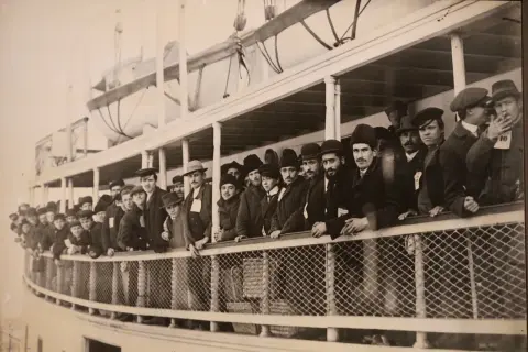 Une foule d'immigrants, hommes et garçons, sur le pont d'un navire, attendant d'arriver à Ellis Island.