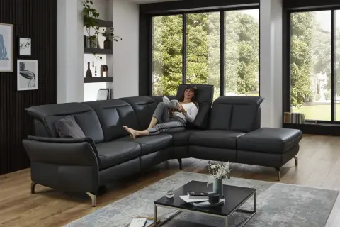 Frau liest auf schwarzem Ledersofa. Dieses Leder ist am robustesten und pflegeleicht, ideal für den Alltag.