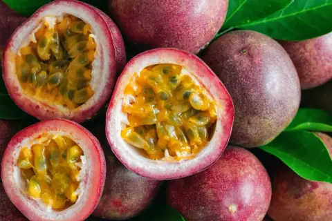 Des fruits de la passion entiers et coupés en deux, révélant leur pulpe juteuse et leurs graines noires. Un délice tropical prêt à être dégusté.