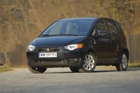 Czarny Mitsubishi Colt 1.3 na drodze, z widocznym numerem rejestracyjnym WW 5979S.