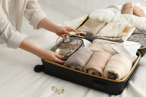 Packa smart för din resa med handbagage. En person organiserar kläder och necessär i en resväska.