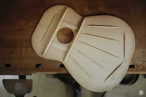 La tapa armónica de una guitarra, hecha de madera de picea, con sus varillas de refuerzo dispuestas para crear un sonido resonante.