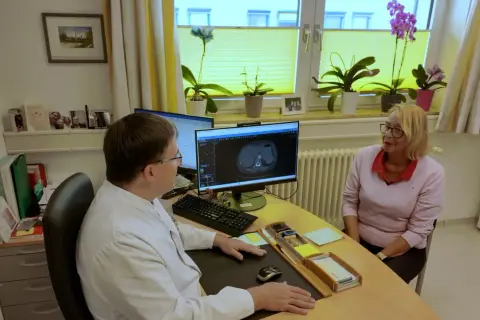 Arzt bespricht CT-Scan mit Patientin. Die Lebenserwartung bei Lungenkrebs Stadium 2 ist ein wichtiges Thema.
