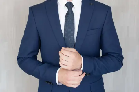 Mężczyzna poprawia mankiet granatowego garnituru na pogrzeb. Elegancki strój podkreśla powagę chwili.