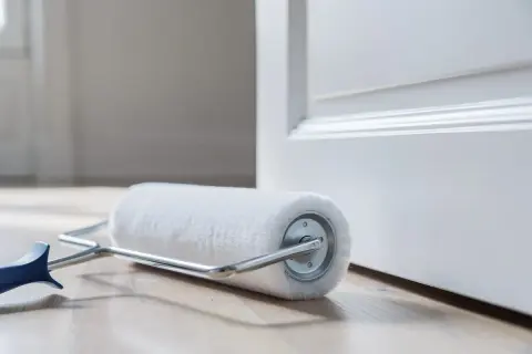 Rouleau de peinture blanc sur parquet, prêt à enlever traces rouleau de peinture sur une porte blanche.