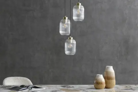 Eleganckie lampy loftowe z przezroczystego szkła wiszą nad marmurowym blatem.
