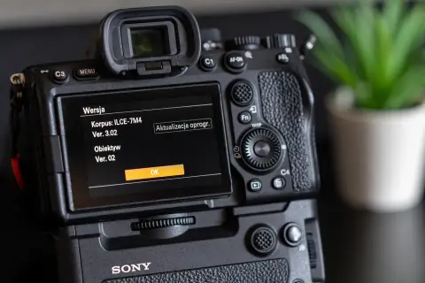 Tył aparatu Sony z ekranem pokazującym wersję oprogramowania korpusu i obiektywu.