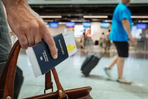 Ręka trzyma paszport i kartę pokładową, gotowa do podróży. Dowiedz się, jak tanio latać i odkrywać świat!