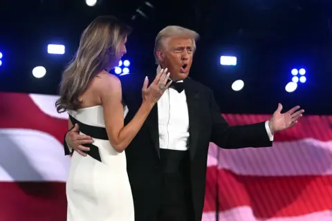 Donald Trump w smokingu, z żoną Melanią, na tle amerykańskiej flagi. Wiek Donalda Trumpa nie jest widoczny na zdjęciu.