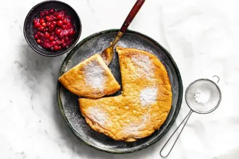 Puszysty omlet z airfryera, posypany cukrem pudrem, podany z żurawiną. Idealny na śniadanie.