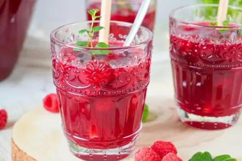 Erfrischende alkoholfreie Bowle mit Himbeeren und Minze in dekorativen Gläsern.