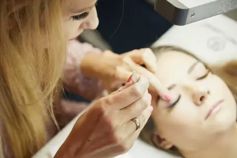 Profesjonalne szkolenie laminacja brwi i rzęs. Stylistka pracuje nad brwiami klientki, tworząc idealny kształt.