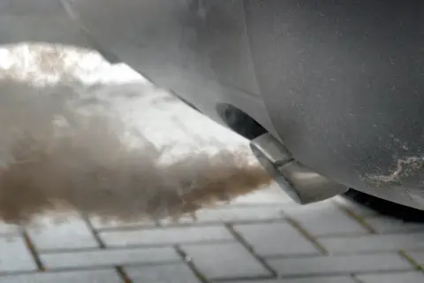 Gęsty dym wydobywa się z rury wydechowej samochodu, co może sugerować problem z DPF. Jak wypalić DPF na postoju, gdy auto kopci?