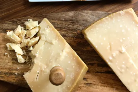 Due pezzi di formaggio stagionato, uno con scaglie e un piccolo tappo di legno, mostrano la differenza tra Gran Biraghi e Grana Padano.