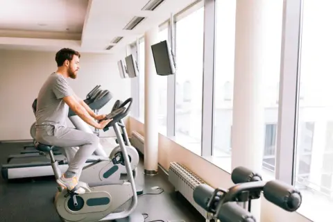 Mężczyzna ćwiczy na rowerze stacjonarnym, co może być pomocne przy zwyrodnieniu stawu biodrowego.
