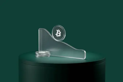Kryptowaluty spadają, symbolizując co to bessa. Bitcoin na szczycie pochylonej platformy, obok stos monet.