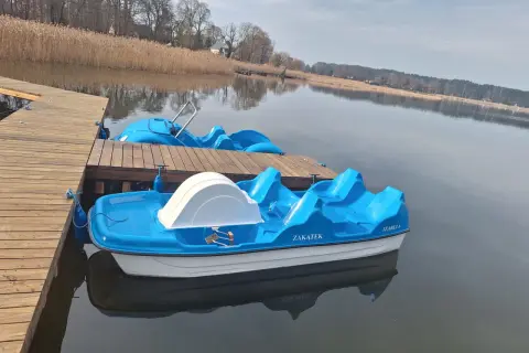 Błękitne rowerki wodne czekają na gości przy drewnianym pomoście. To idealne miejsce na wypoczynek, jak w słynnym polu namiotowym Sława.