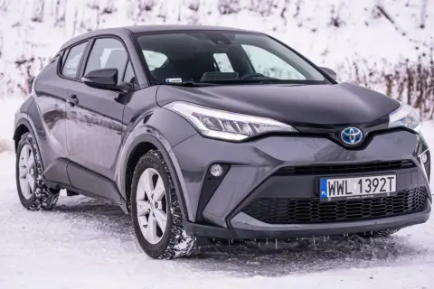 Szara, używana Toyota C-HR na śniegu. Stylowy crossover gotowy na zimowe wyzwania.