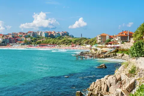 Słoneczne bułgaria plaże z turkusową wodą, kamienistym wybrzeżem i kolorowymi budynkami na wzgórzu.