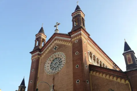 La chiesa San Dalmazzo a Torino, con le sue torri e il rosone, si staglia contro il cielo azzurro.