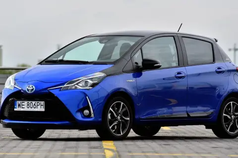 Niebieska Toyota Yaris Hybrid z czarnym dachem, zaparkowana na zewnątrz.