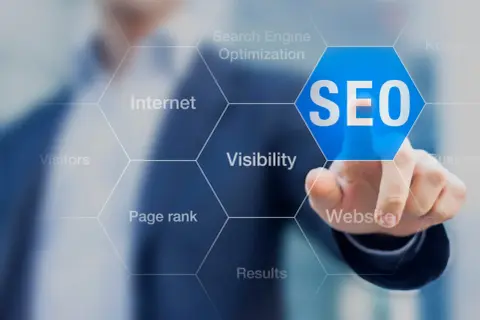 Palec wskazuje na niebieski sześciokąt z napisem SEO. Wokół widoczne są hasła: Internet, Search Engine Optimization, Keywords, Visibility, Website, Results, Page rank, Visitors. To podpowiedź, jak zbadac element.