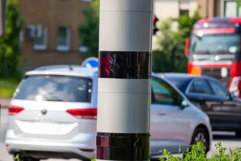 Ein Blitzer ohne Blitz: Dieses Gerät überwacht den Verkehr. Autos fahren vorbei, ein roter LKW ist im Hintergrund zu sehen.