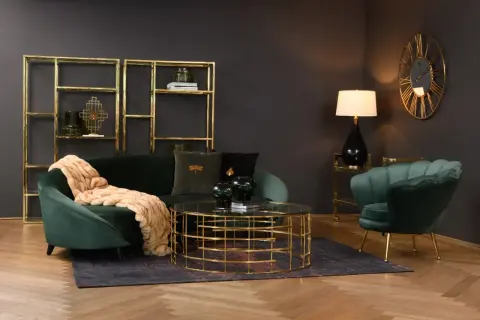 Butelkowa zieleń w salonie: aksamitna sofa i fotel, złote regały i stolik kawowy tworzą elegancką całość.