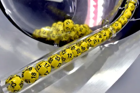 Żółte kulki z numerami, jak w grze multi multi zasady, toczą się w przezroczystej tubie.