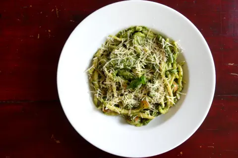 Assiette de trofie au pesto, garnie de parmesan râpé. Une recette italienne savoureuse et colorée.
