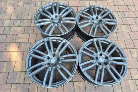 Cztery felgi do Maserati Ghibli SQ4, szare, z charakterystycznym wzorem, leżą na kostce brukowej.