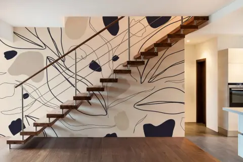 Escalier moderne avec un mur à l'effet peinture, orné de formes abstraites et de lignes organiques dans des tons neutres.