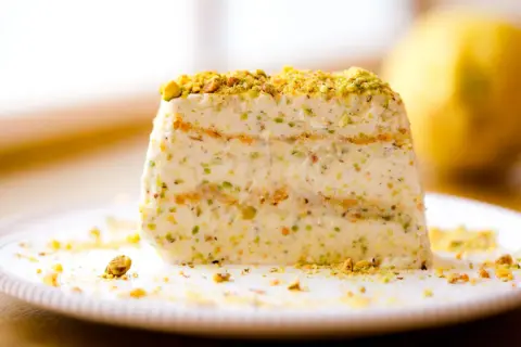 Ein Stück cremiges Semifreddo al Pistacchio, bestreut mit gehackten Pistazien, auf einem Teller.