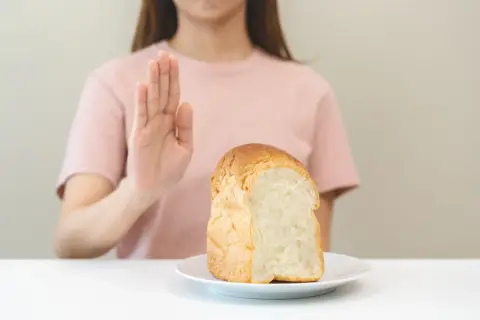 Kobieta odrzuca chleb, symbolizując dietę bezglutenową.