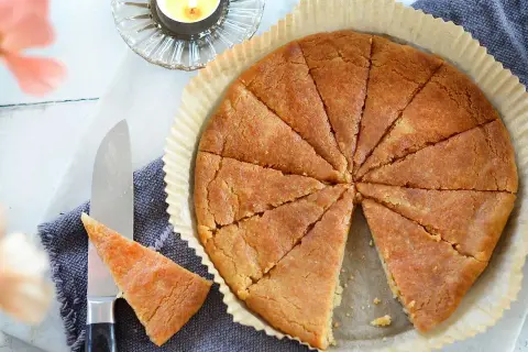 En gyllene, uppskuren kolakaka i en form. Ett recept på kolakakor som ser ljuvligt ut. En ljuslykta och en kniv med en bit kaka.