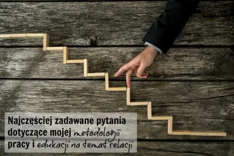 Palce wskazujące mężczyzny w garniturze schodzą po drewnianych schodkach, symbolizując podróż wgłąb siebie i analizę metod pracy.