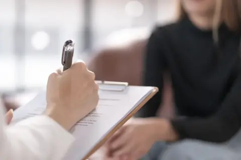 Psycholog prowadzi diagnozę różnicową, notując spostrzeżenia podczas rozmowy z pacjentem.
