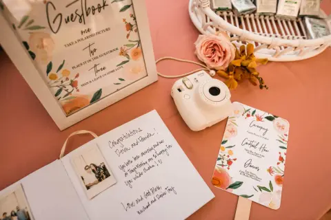Wpis do księgi gości z polaroidami i życzeniami. Aparat Instax czeka na uwiecznienie chwil.