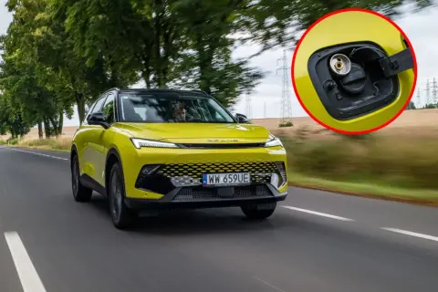 Żółty SUV z fabrycznym LPG na drodze. W powiększeniu widać korek wlewu gazu.
