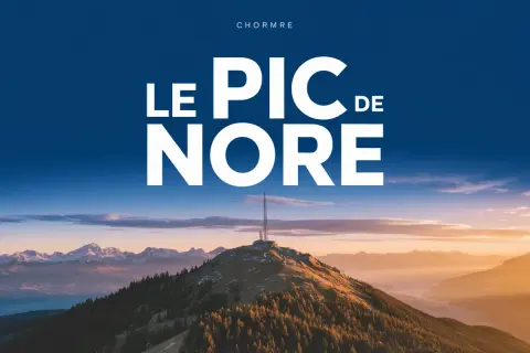 Le pic de Nore, sommet majestueux sous un ciel bleu, dominé par une antenne. Paysage montagneux au coucher du soleil.