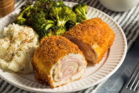 Un delicioso cordon bleu, crujiente por fuera y jugoso por dentro, acompañado de puré de patatas y brócoli.