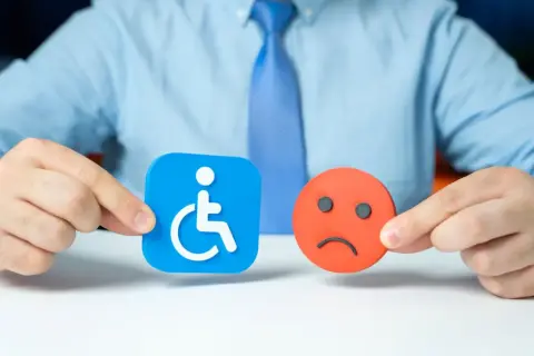 Osoba z niepełnosprawnością symbol na niebieskim tle i smutna buźka na czerwonym.
